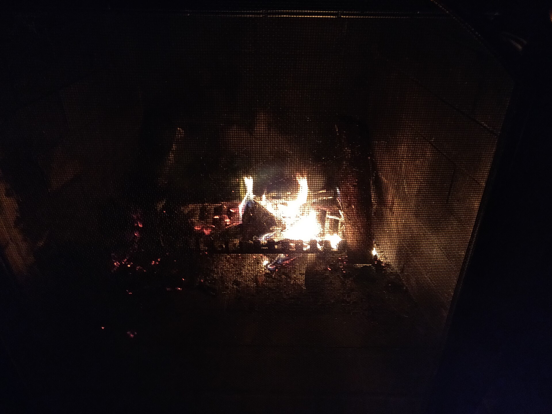 Oak logs burning low in a red brick fireplace with a clean firebox